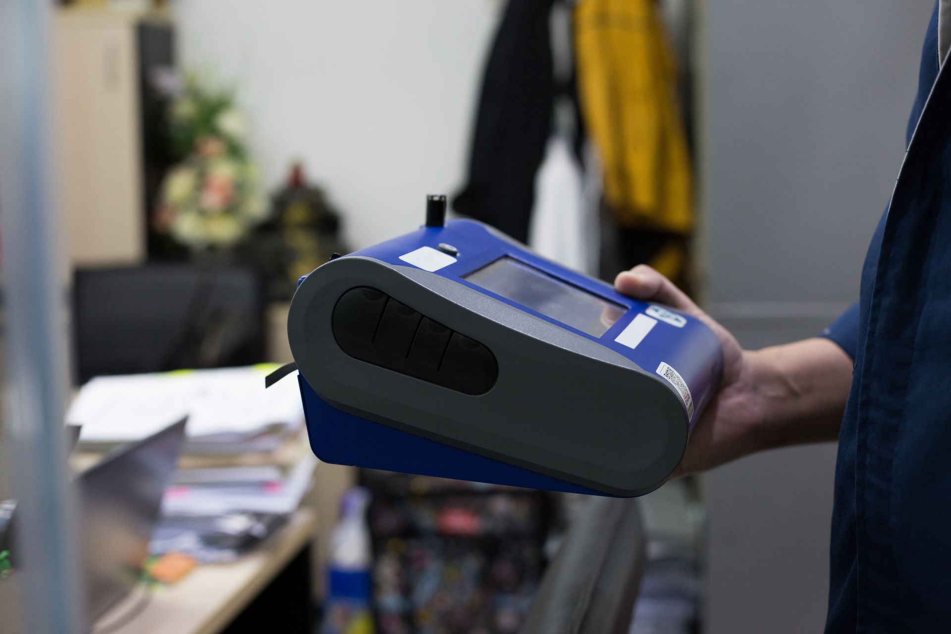 A man is holding a blue and gray device in his hand.