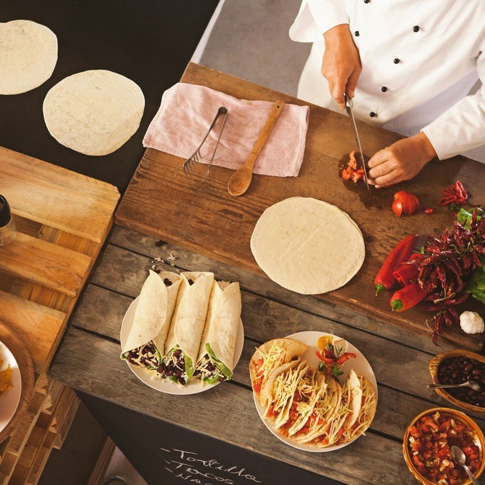 Un chef está preparando tacos en una mesa de madera.