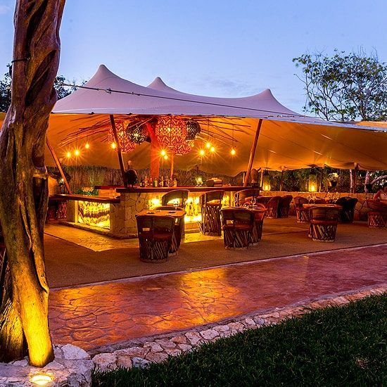 Un restaurante con mesas y sillas bajo una carpa por la noche.