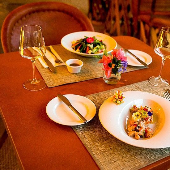 Una mesa con platos de comida y copas de vino encima.