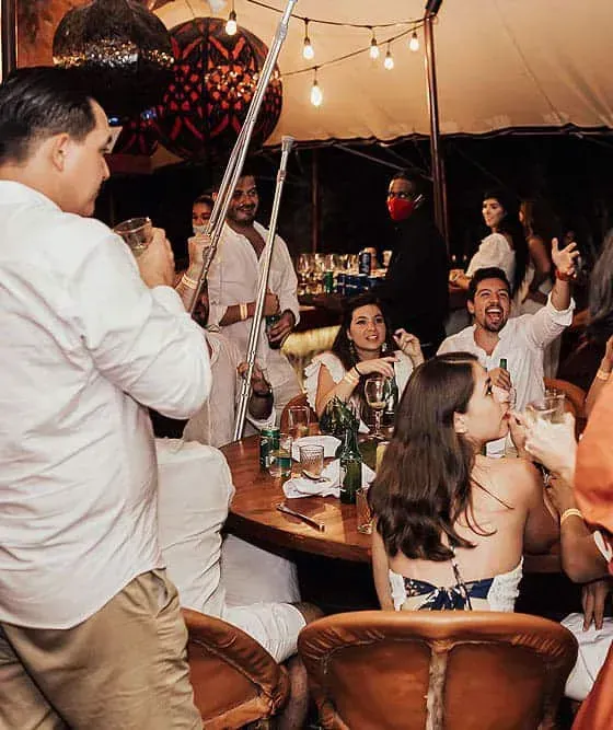 Una sombrilla roja reposa sobre una mesa y sillas en la playa.