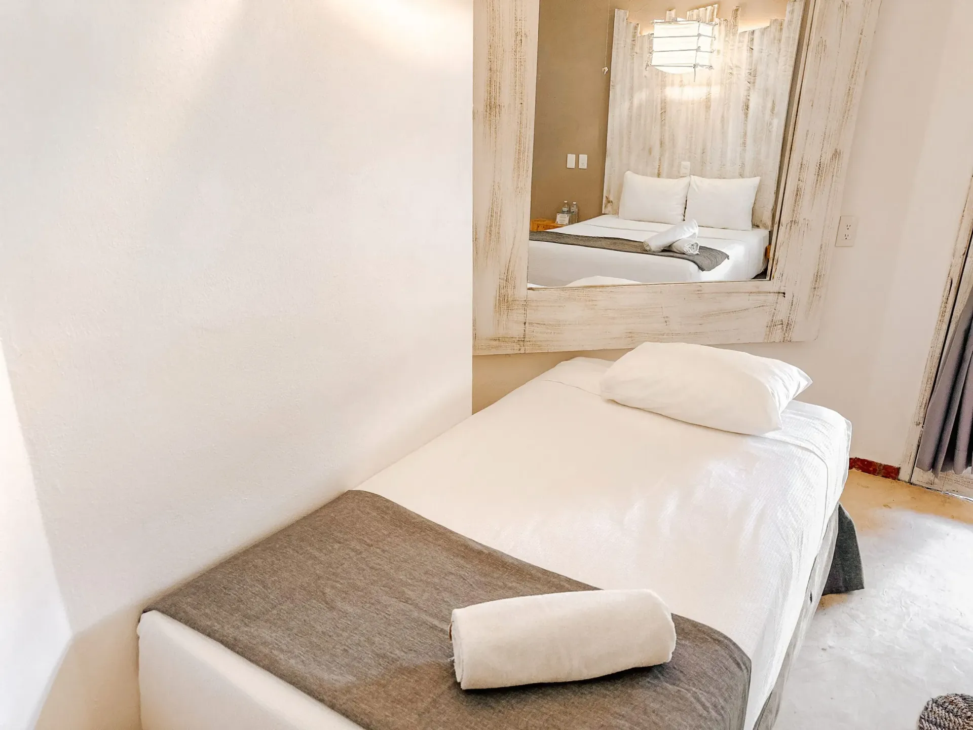 Sala de spa con camilla de masaje y alcoba decorativa con cama.