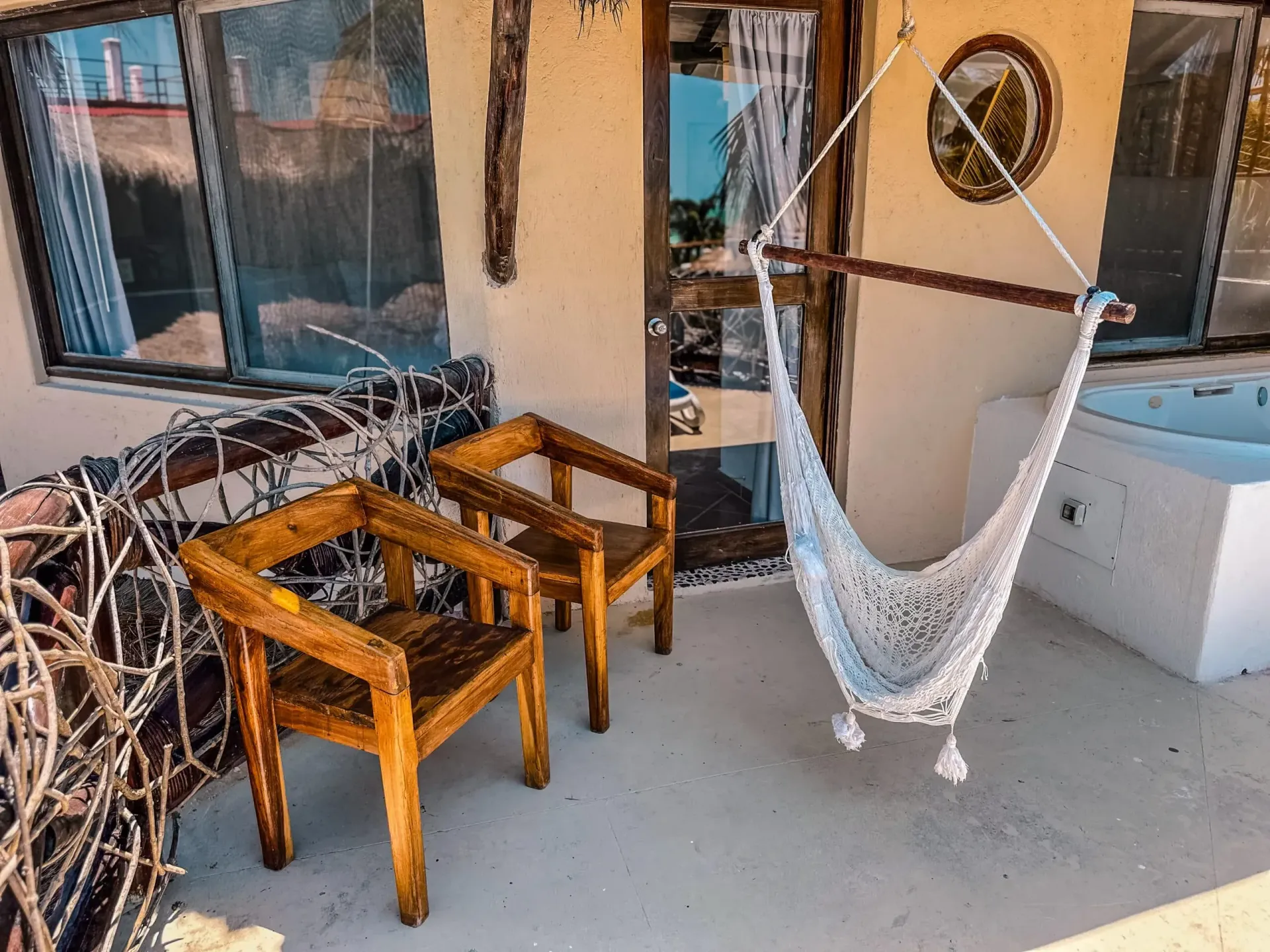 Dos sillas de madera y una hamaca colgante en un patio.