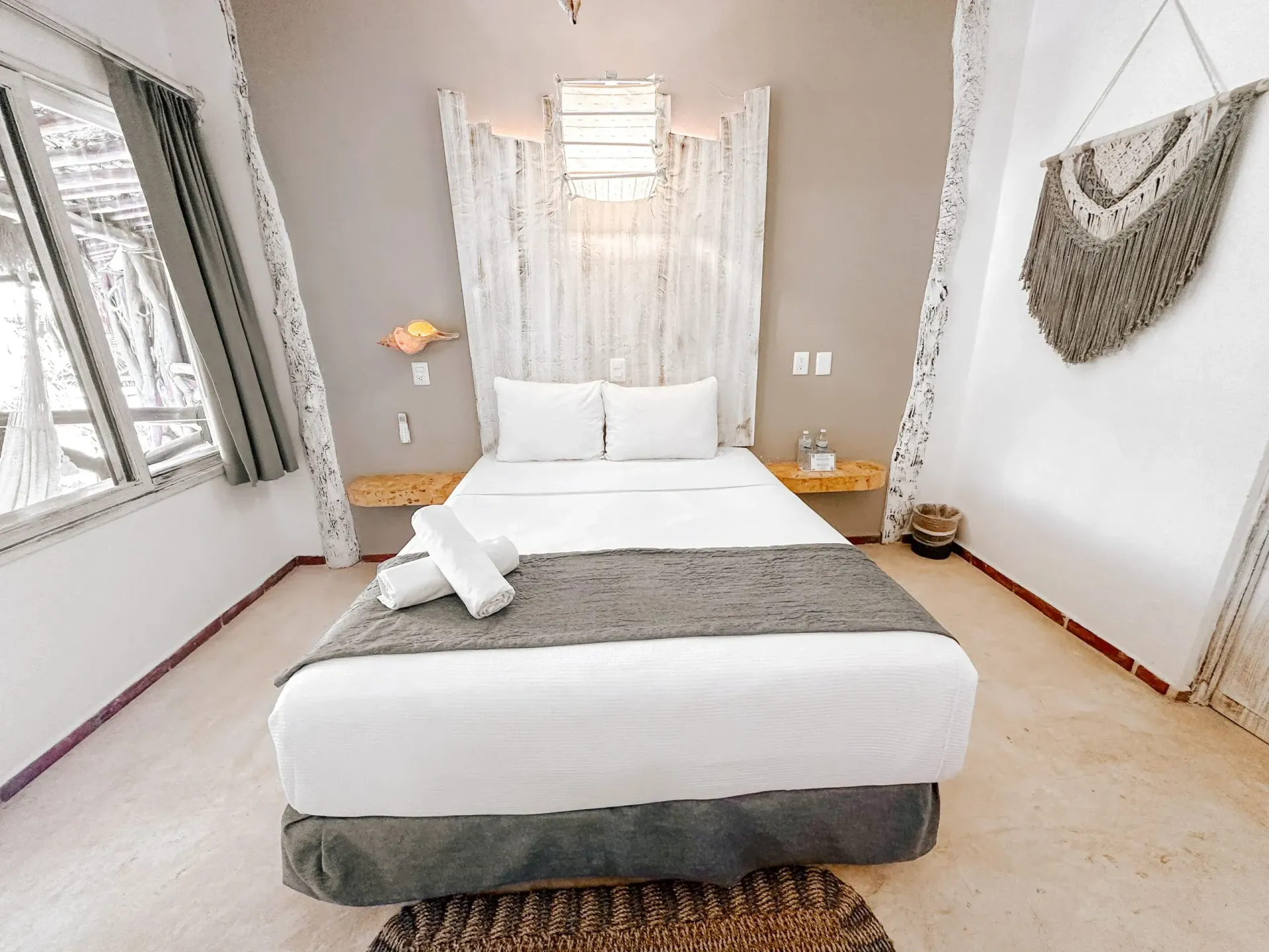 Dormitorio con paredes blancas, cama, cabecero de madera y alfombra decorativa.