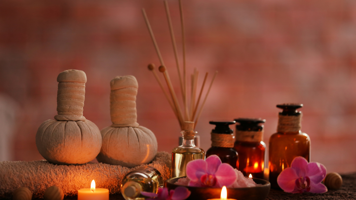 Spa scene with essential oils, candles, and massage tools, lit with warm light.