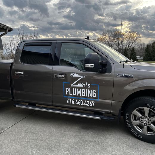 A truck with the word plumbing on the side is parked in a driveway.