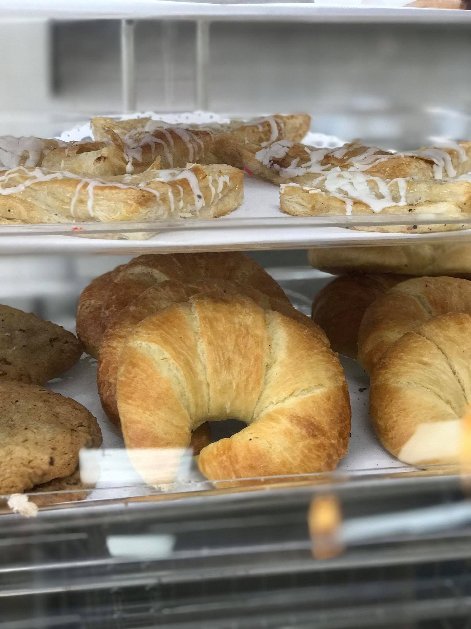 A display case filled with croissants and pastries in a bakery.