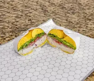 A sandwich is cut in half on a white plate on a table.