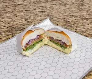 A sandwich is cut in half on a white plate on a table.