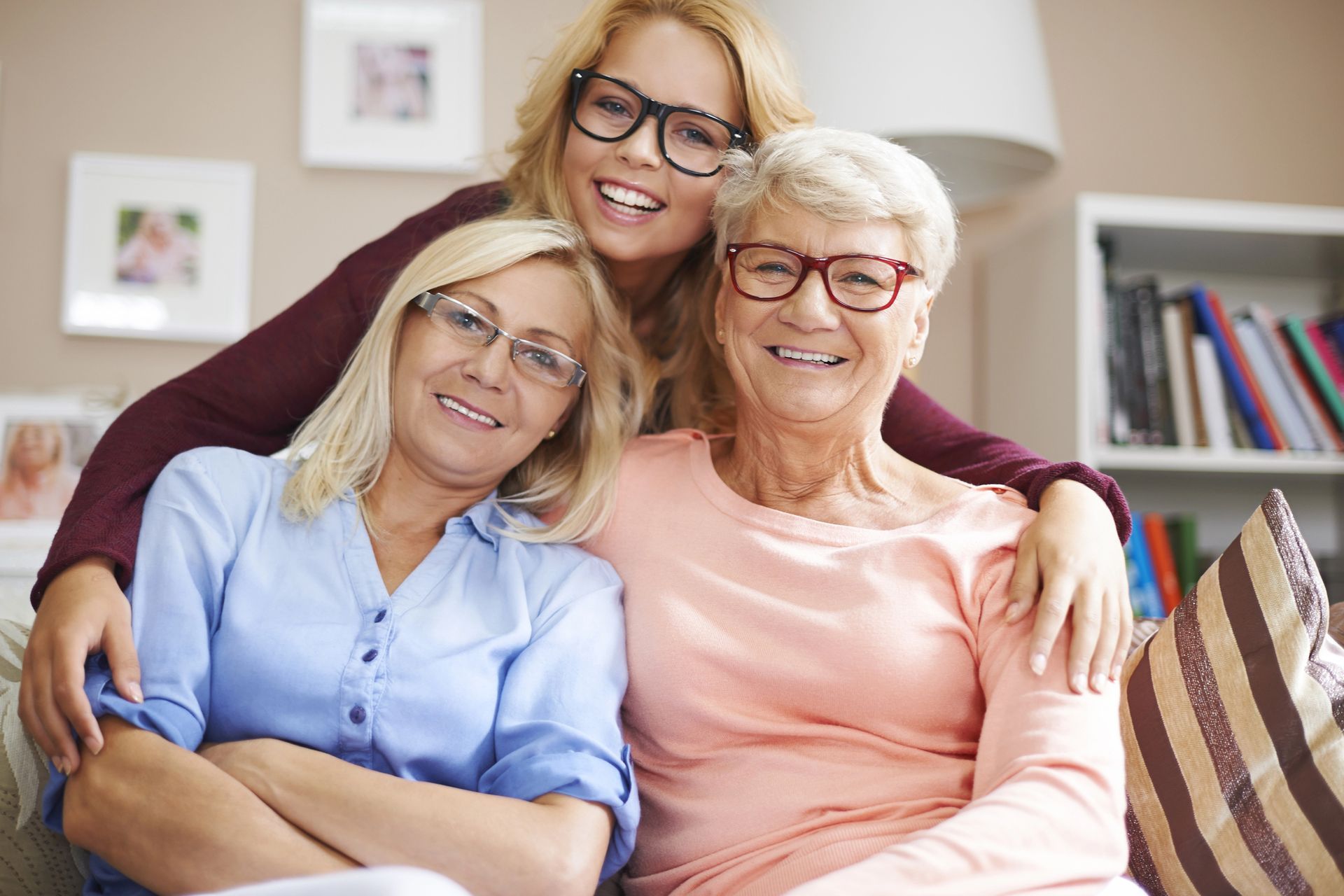 Three women are posing for a picture while sitting on a couch.