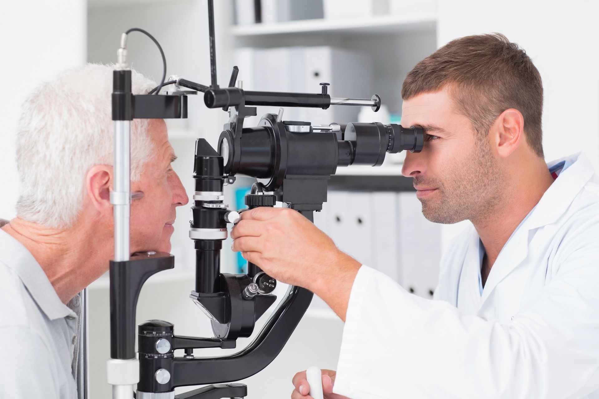 An older man is getting his eyes examined by an ophthalmologist.