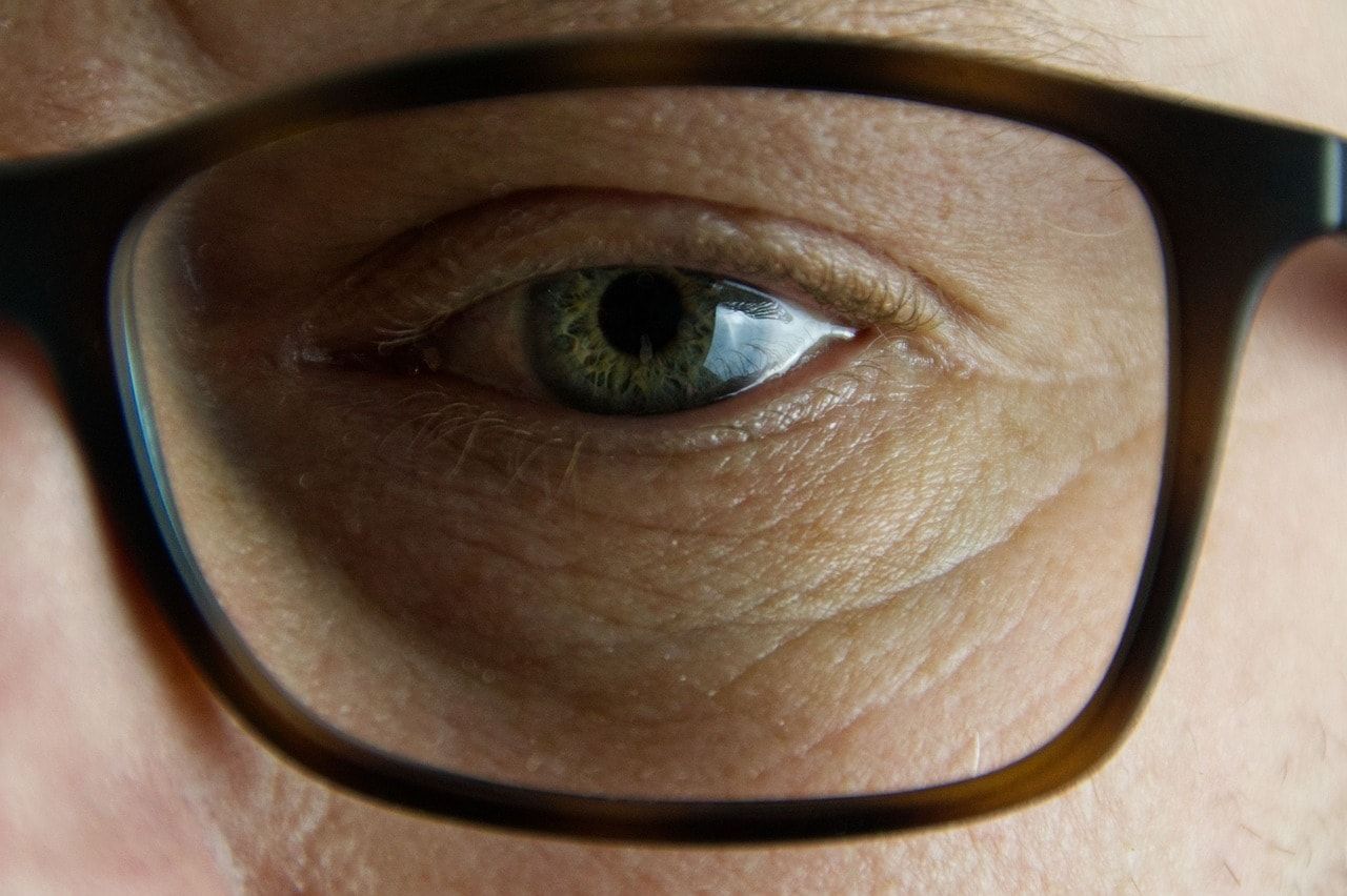 A close up of a person 's eye wearing glasses.