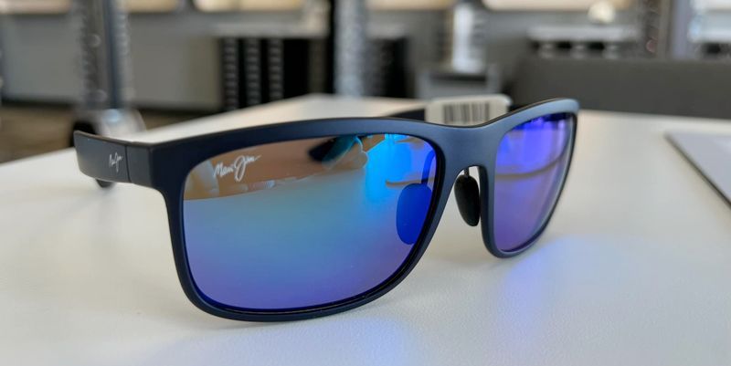 A pair of sunglasses with blue lenses are sitting on a white table.