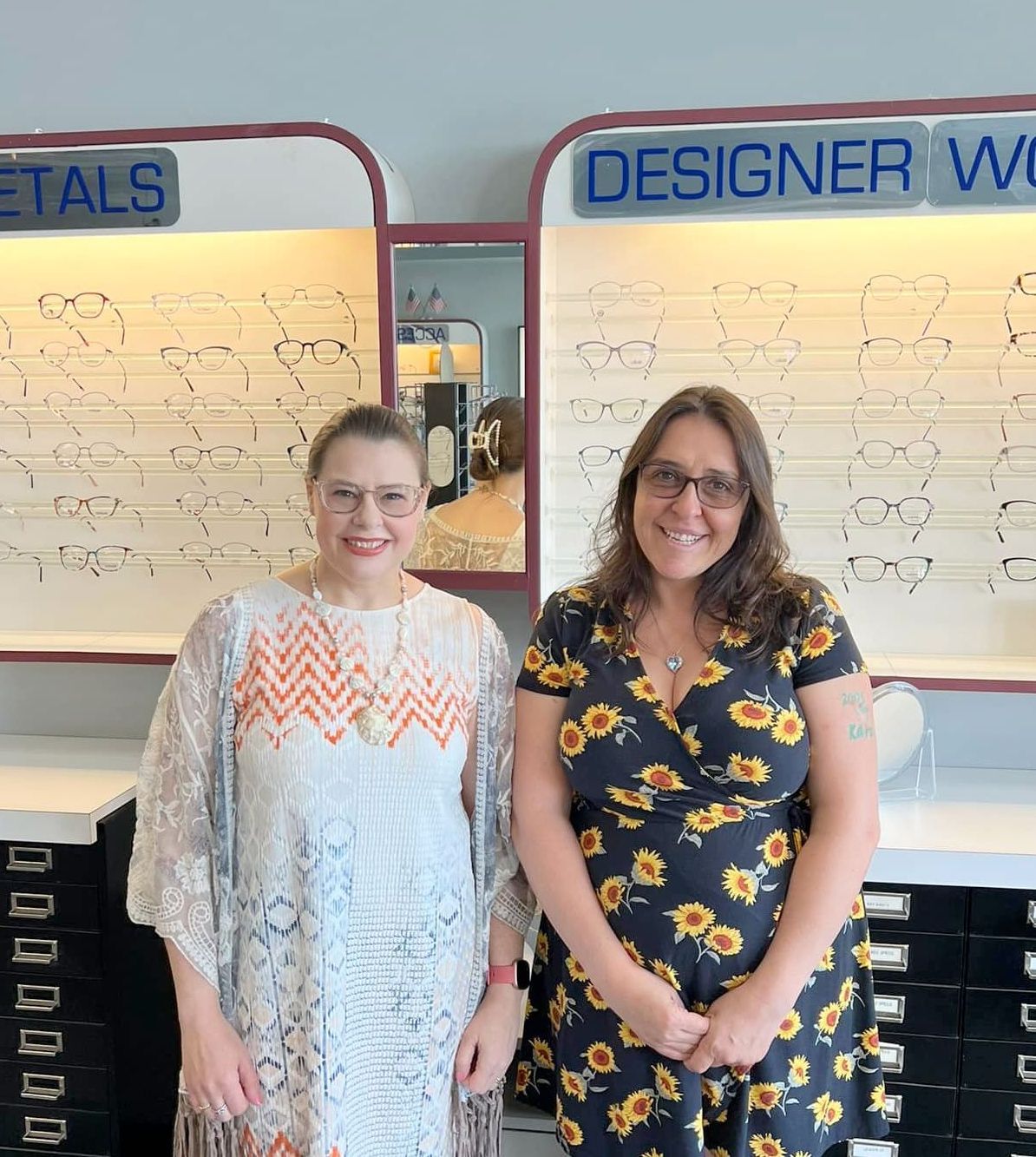 Two women standing in front of a display of designer glasses