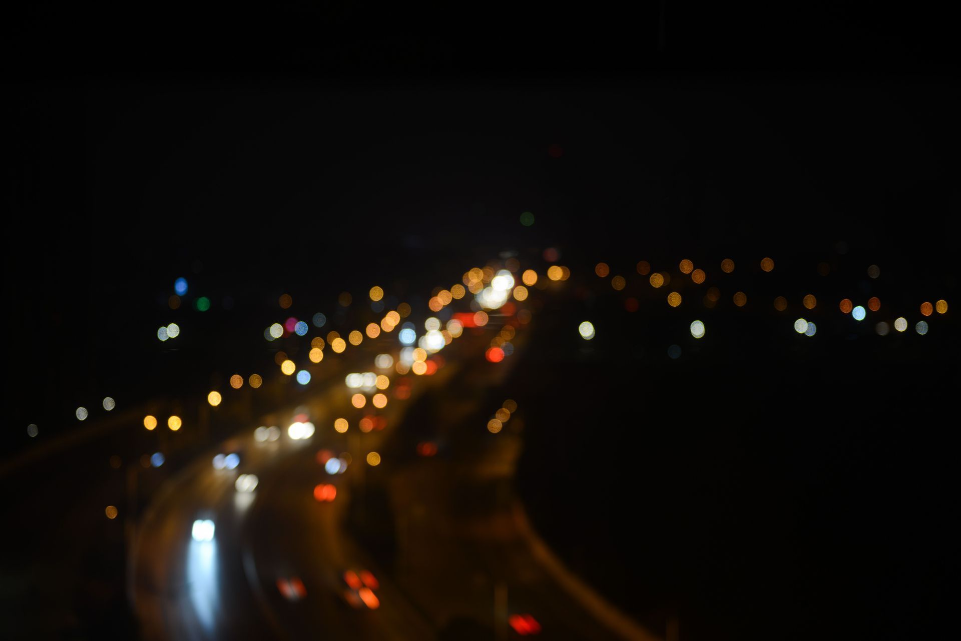 Blurred nighttime highway traffic with glowing headlights and taillights stretching into the distance