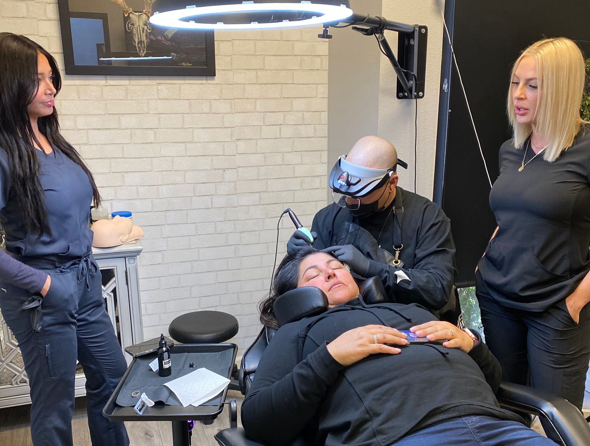 An SMP INK CDA Student Practitioner drawing the reference line on the scalp of  an SMP client in a class setting.