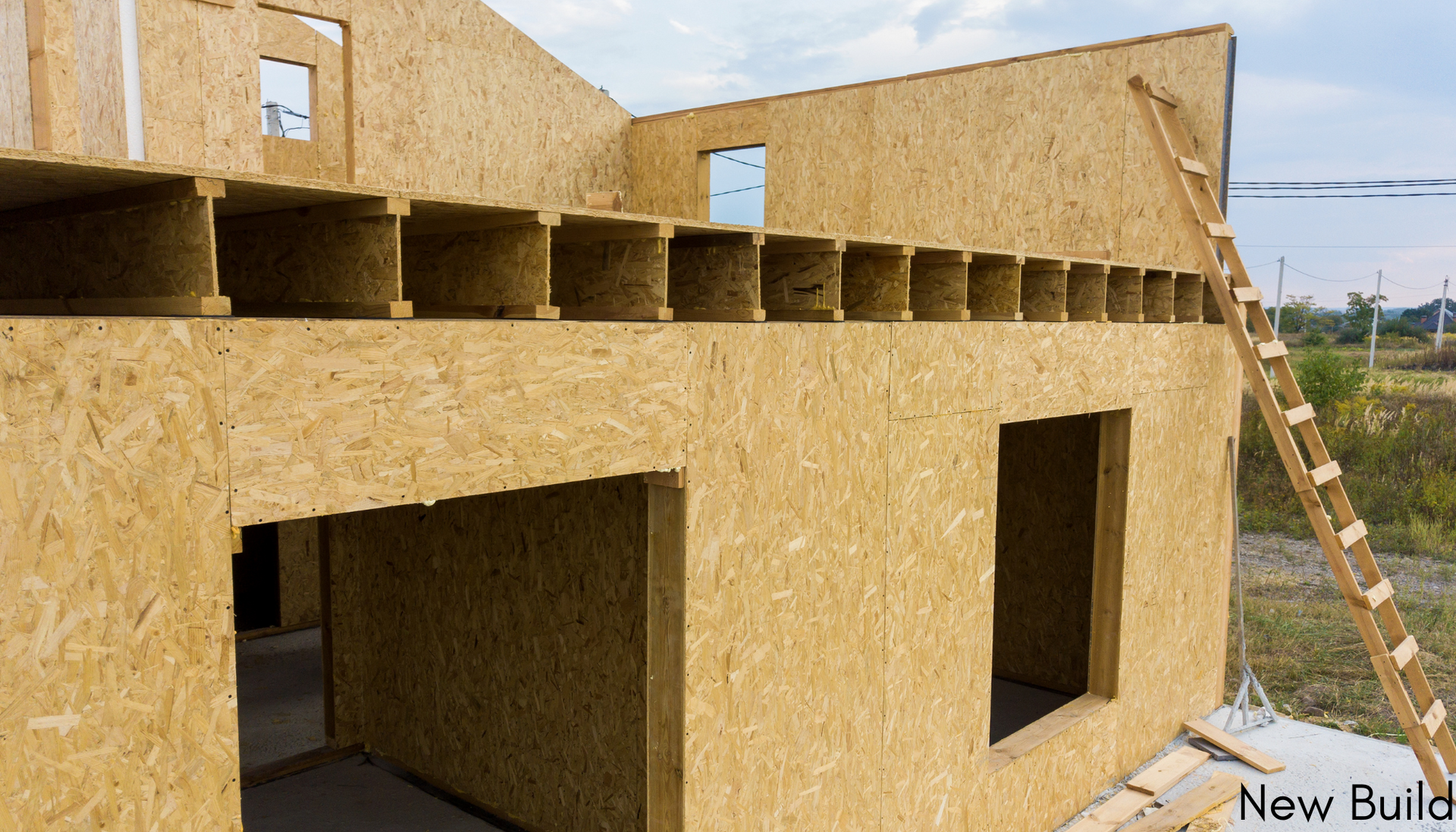 A wooden house is being built with a ladder on the side.
