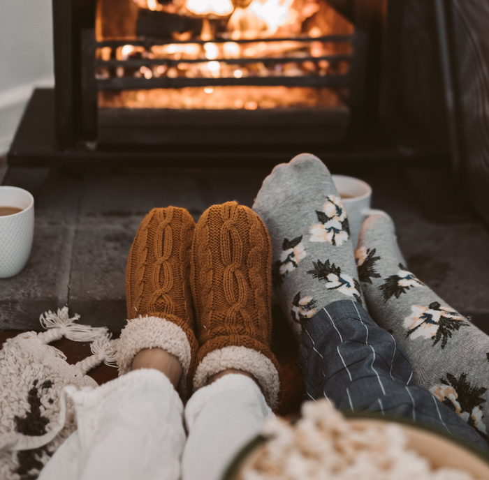 A couple is sitting in front of a fireplace wearing socks