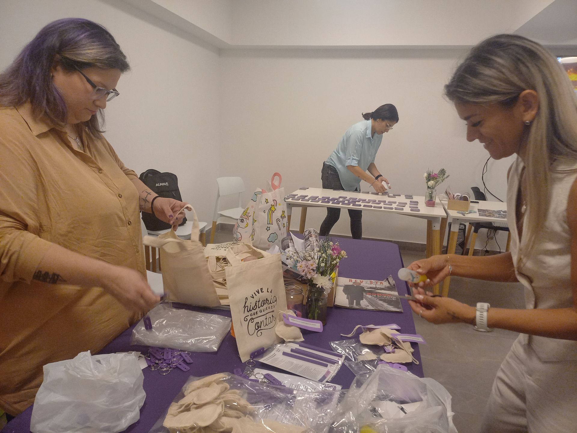 Dos mujeres están sentadas en una mesa haciendo manualidades.