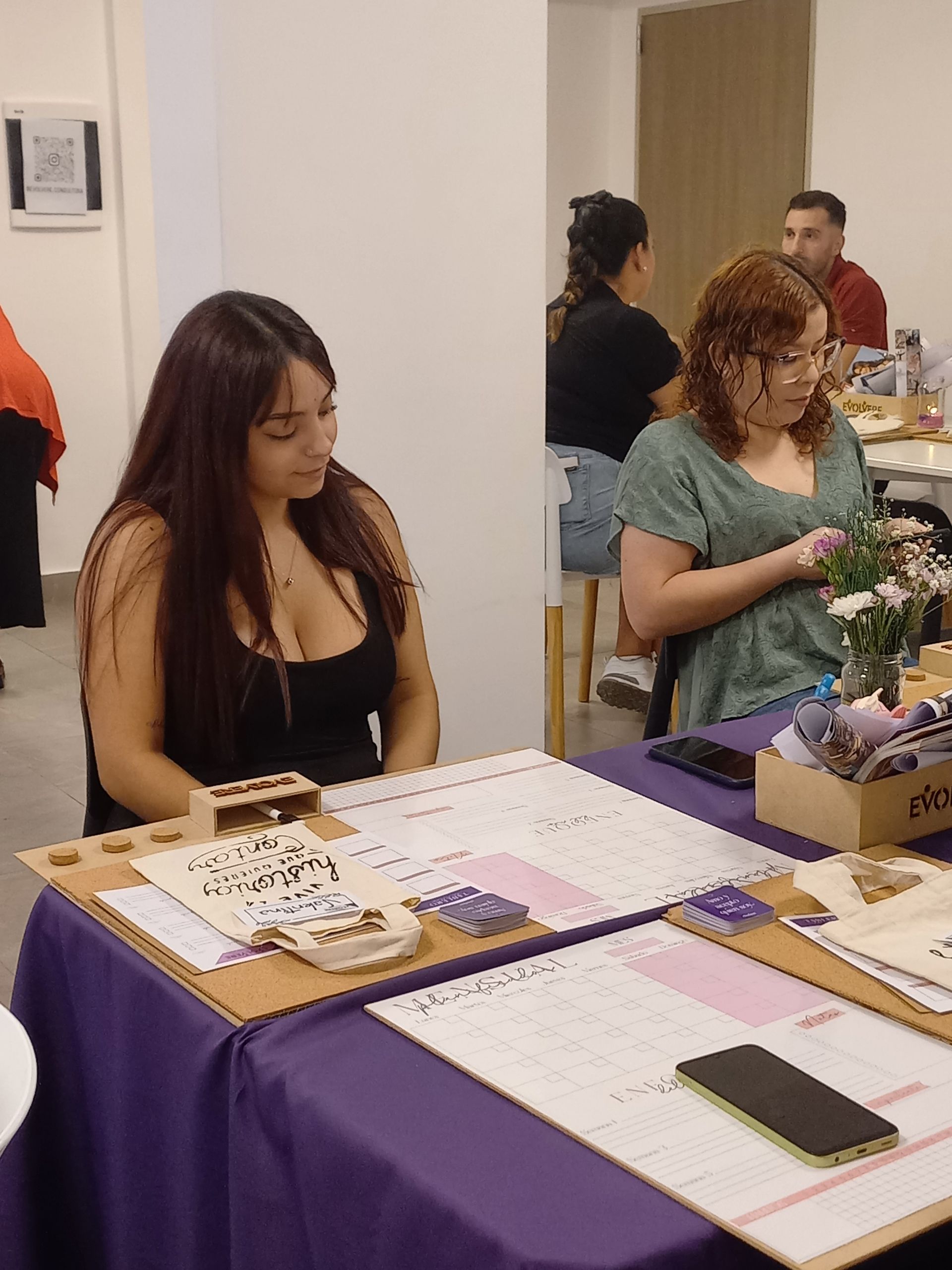 Una mujer está sentada en una mesa con un mantel morado.