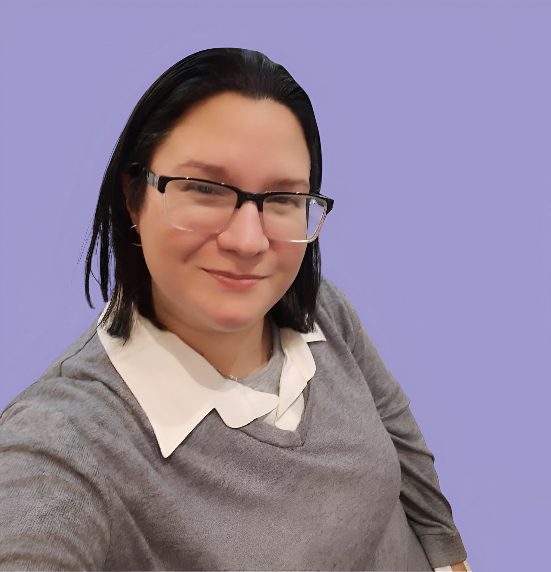 Una mujer con gafas y un suéter gris se toma una selfie