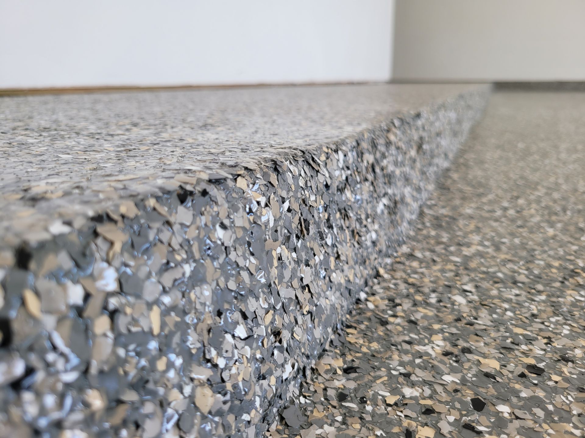 A close up of a concrete floor with a white wall in the background.