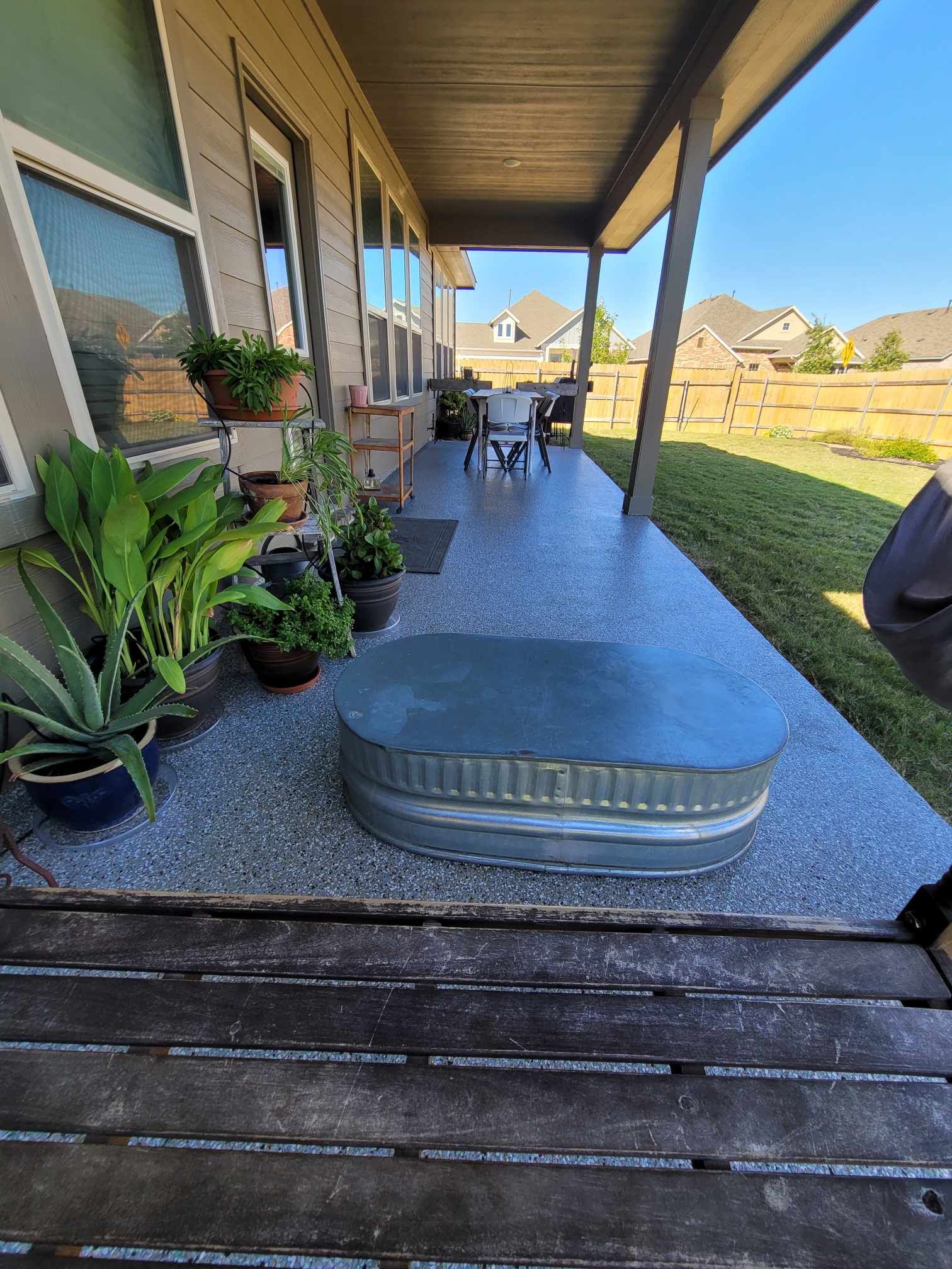 A porch with a table and chairs and plants on it.