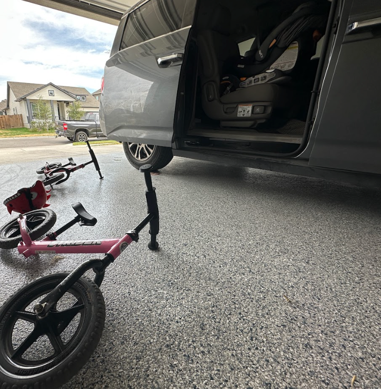 A car is parked in a garage with a car seat in the back.