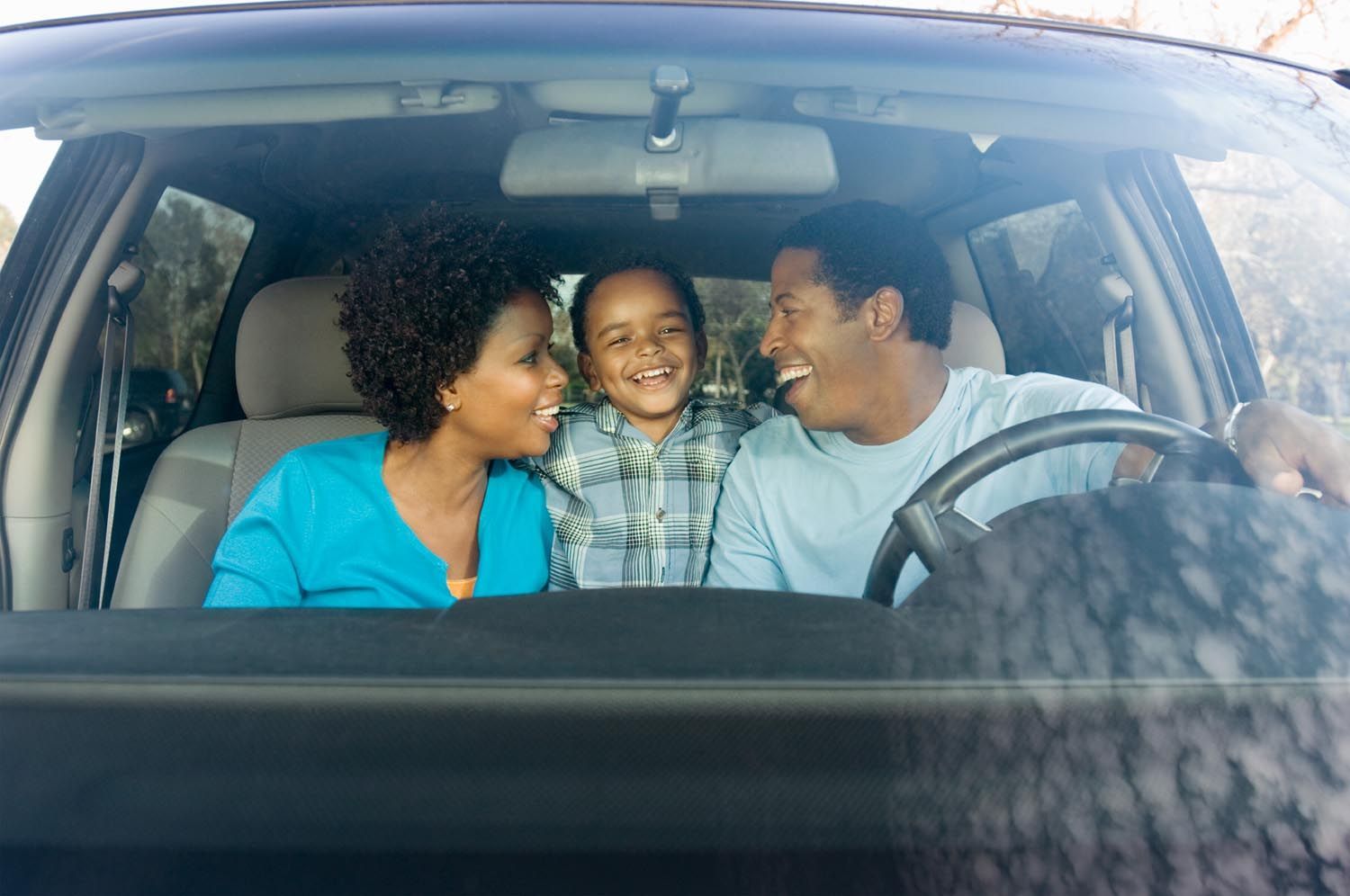 Family smiling in a car, looking at each other.