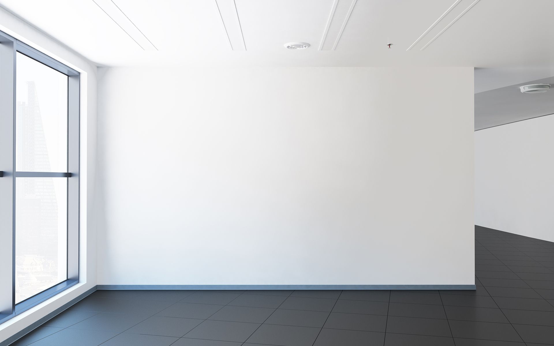 An empty room with a large window and a black floor.