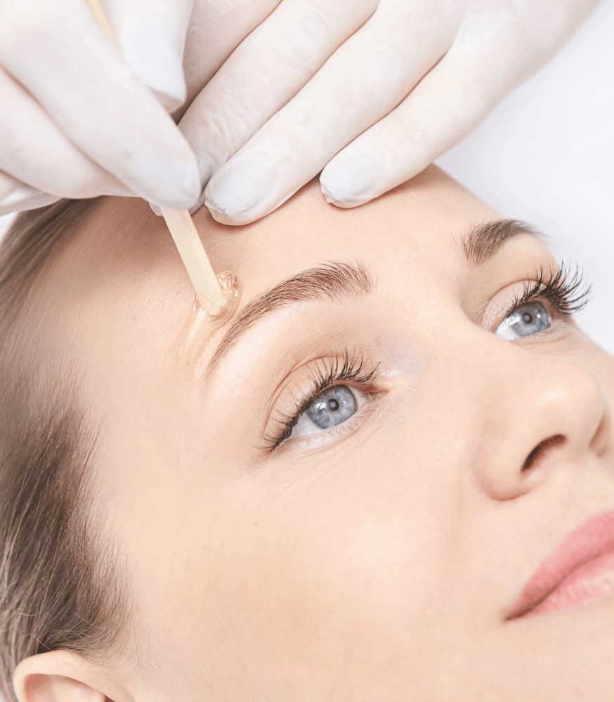 Une femme se fait épiler les sourcils avec un bâton en bois