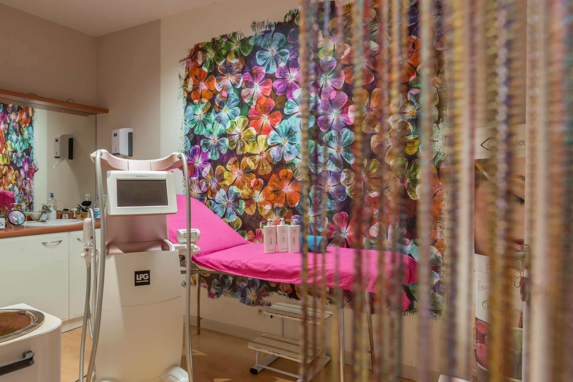 Une chambre avec un lit rose et un mur avec des fleurs dessus.