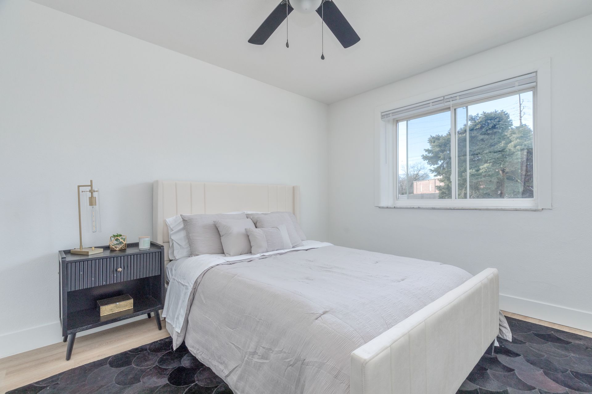 A bedroom with a bed , nightstand , and ceiling fan.