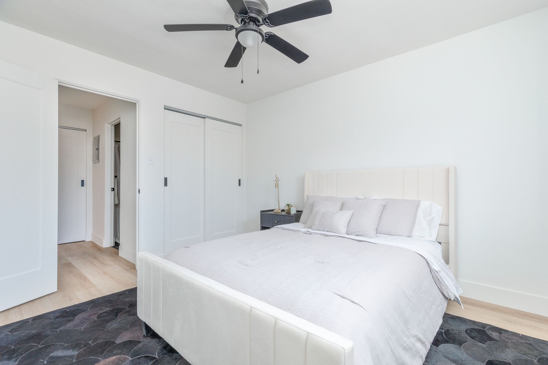 A bedroom with a large bed and a ceiling fan.