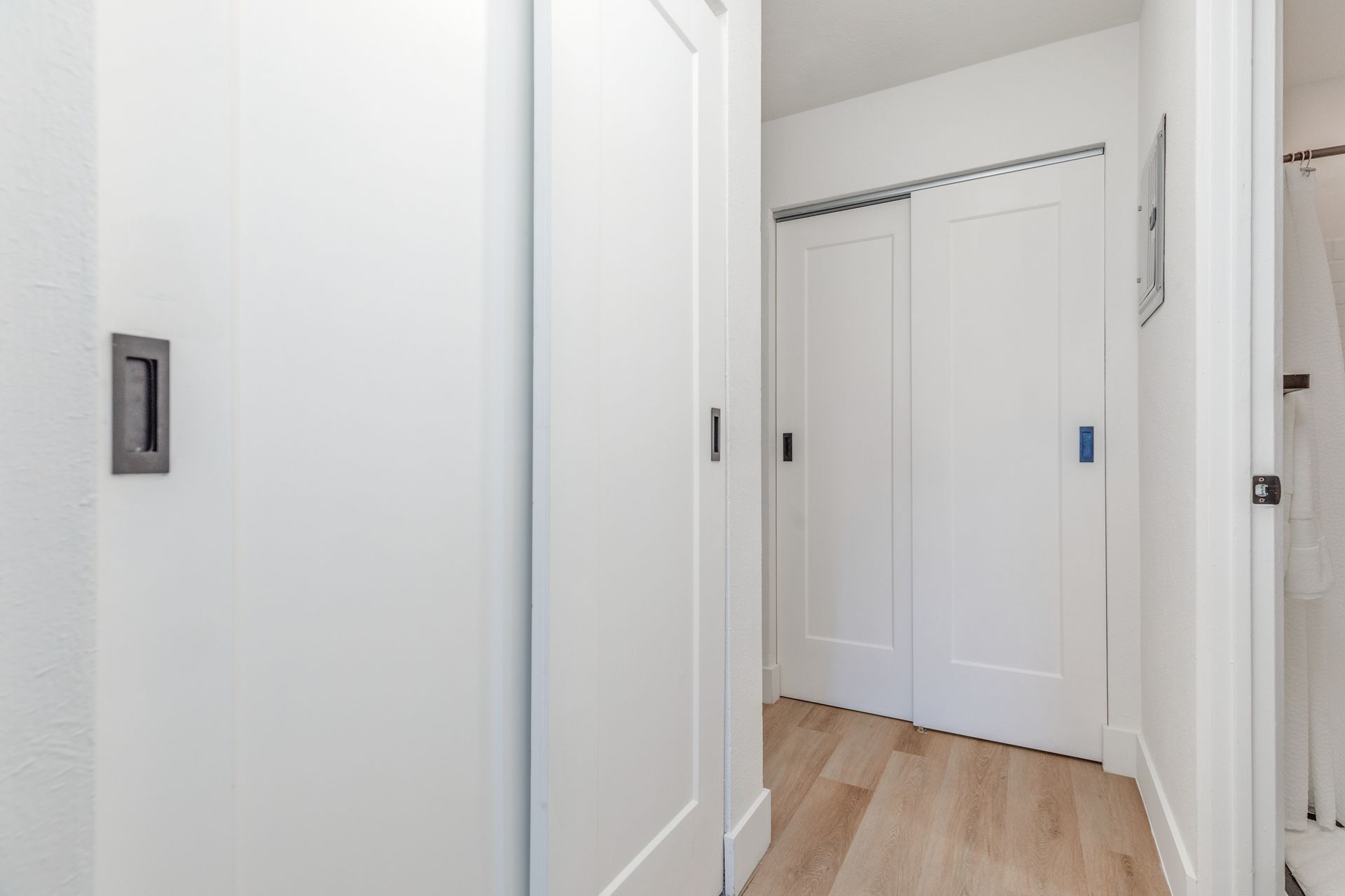 A hallway with sliding doors and hardwood floors in a house.