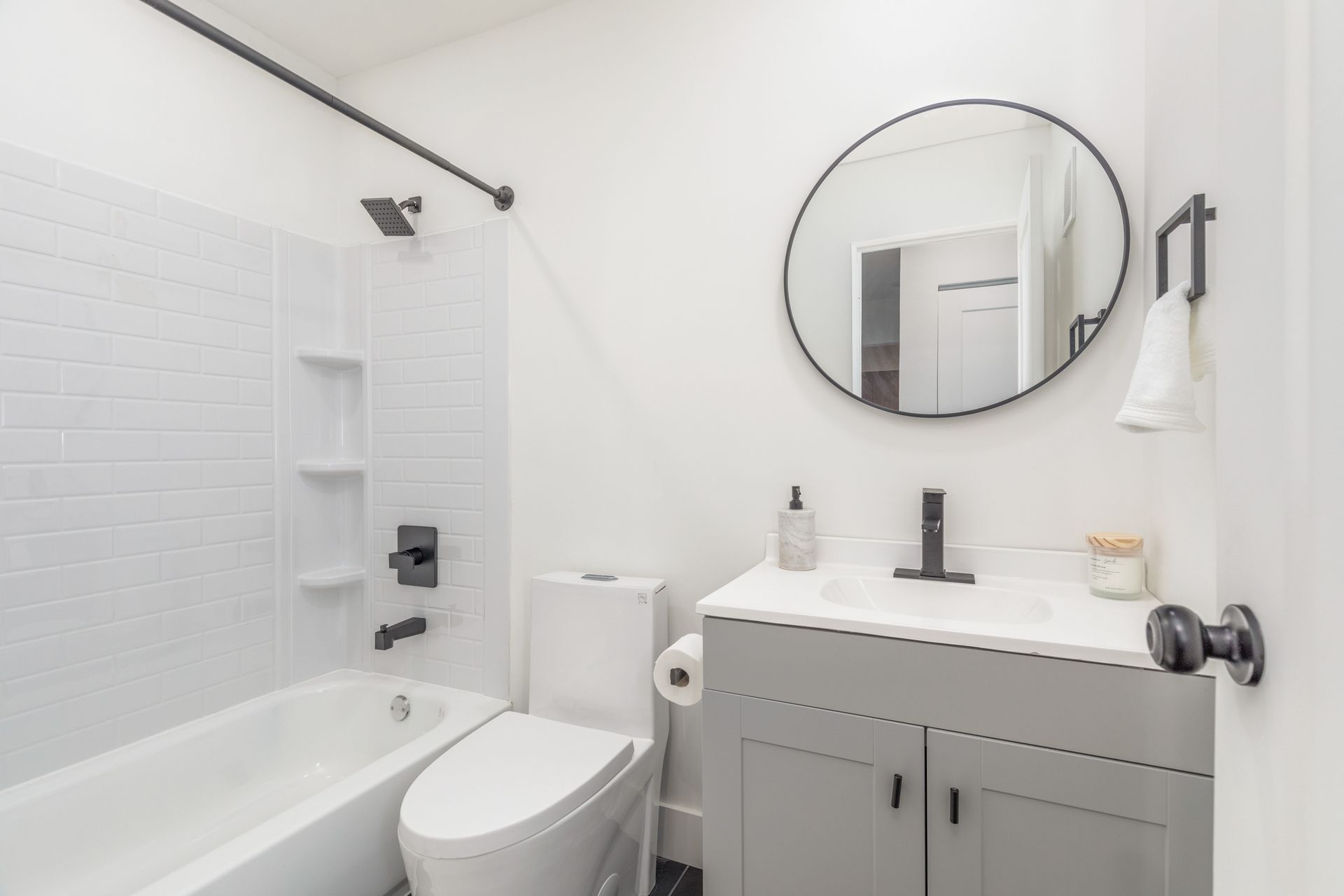 A bathroom with a toilet , sink , bathtub and mirror.