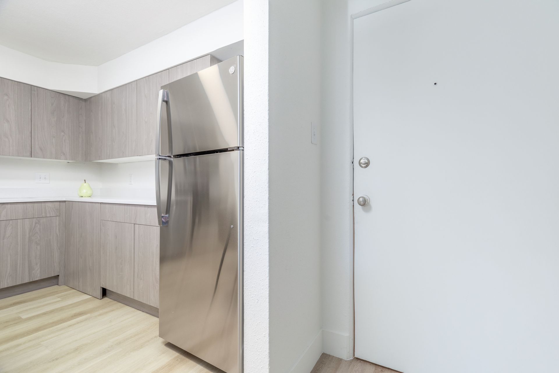 A kitchen with a stainless steel refrigerator and a white door.