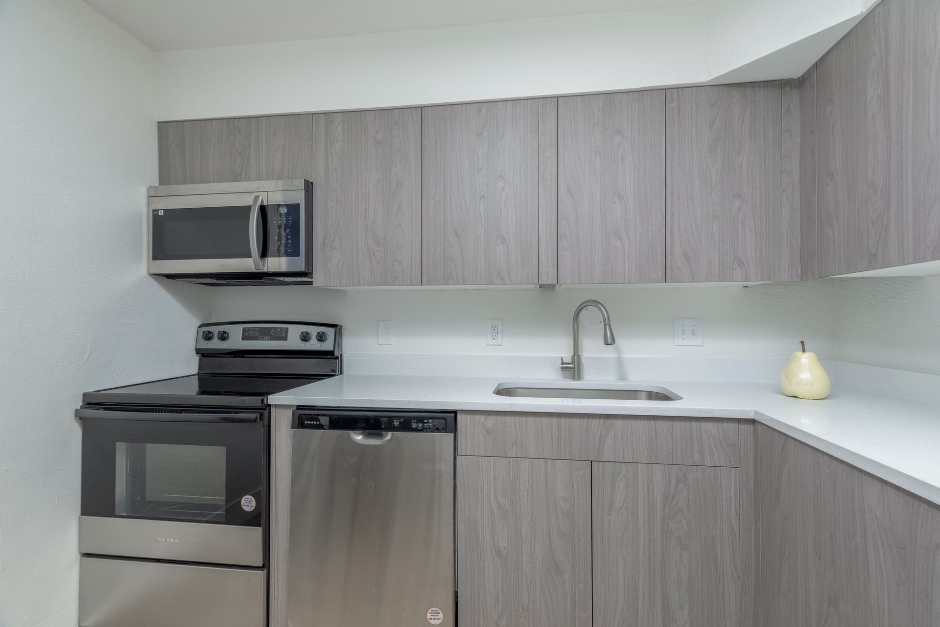 A kitchen with stainless steel appliances and gray cabinets.