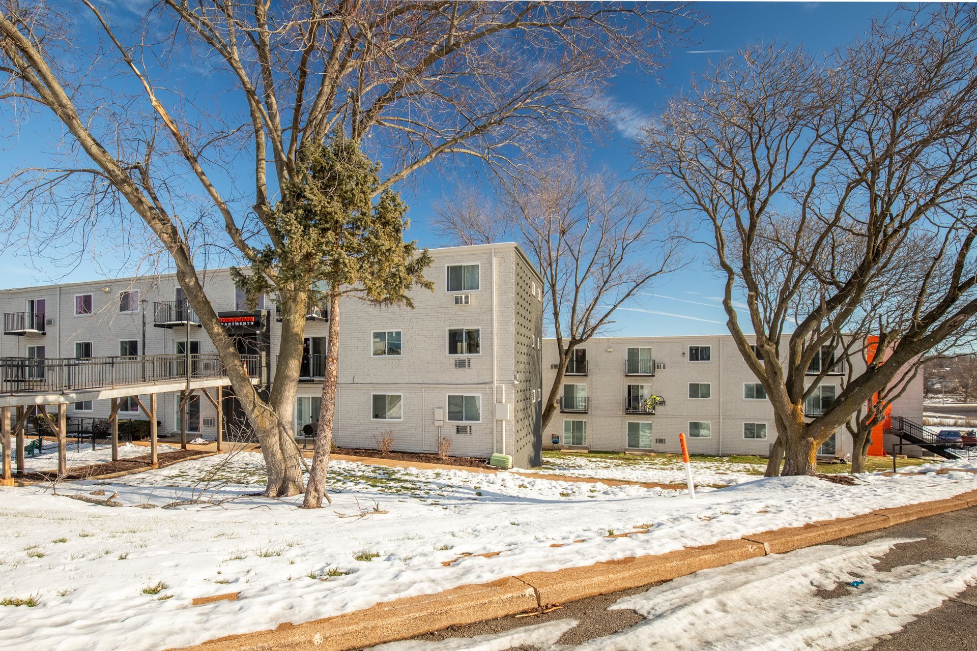 A large building with a lot of windows is surrounded by snow and trees.