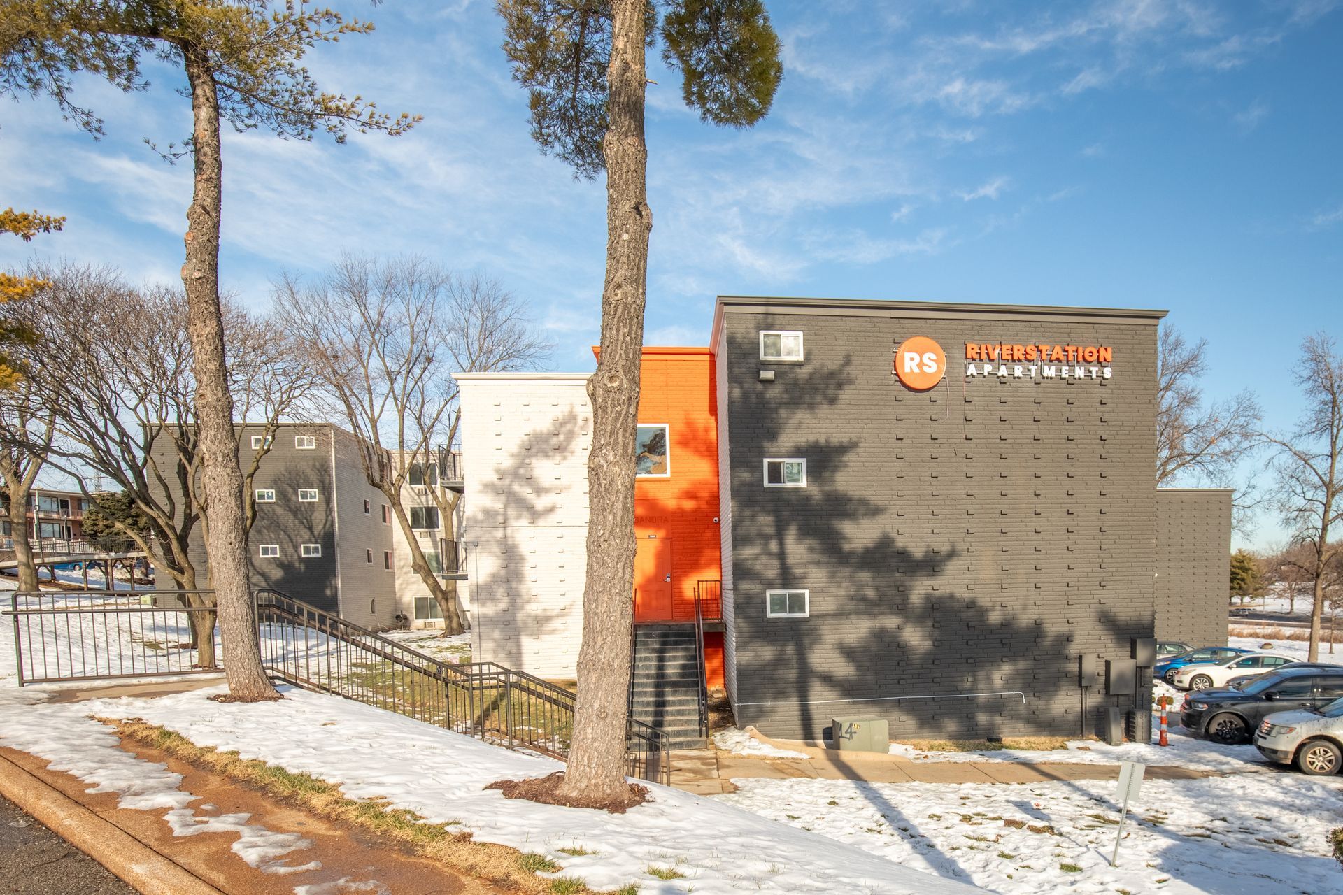 A large building with a lot of windows is surrounded by snow and trees.