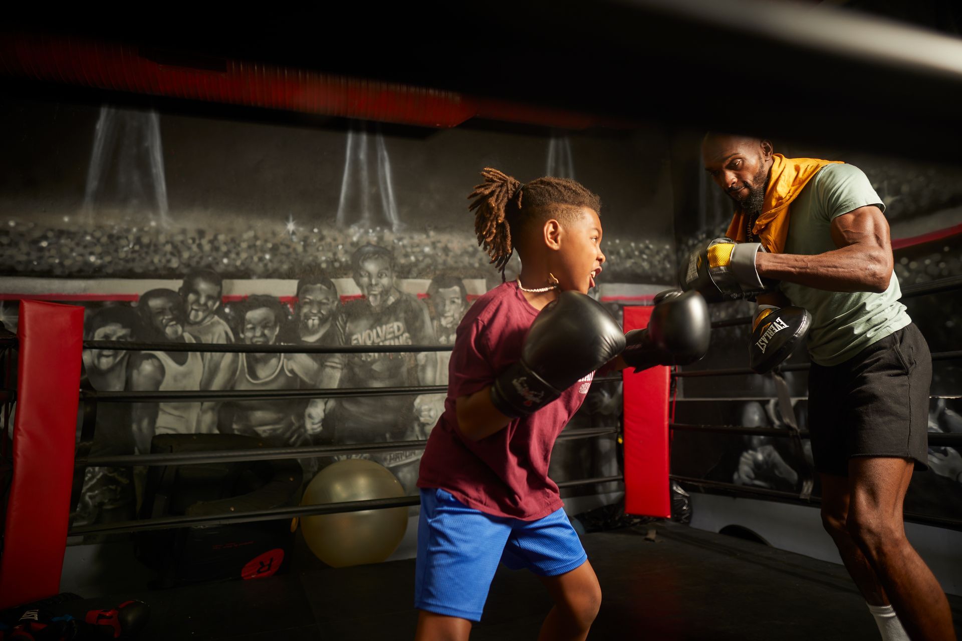 A man and a boy are boxing in a boxing ring.