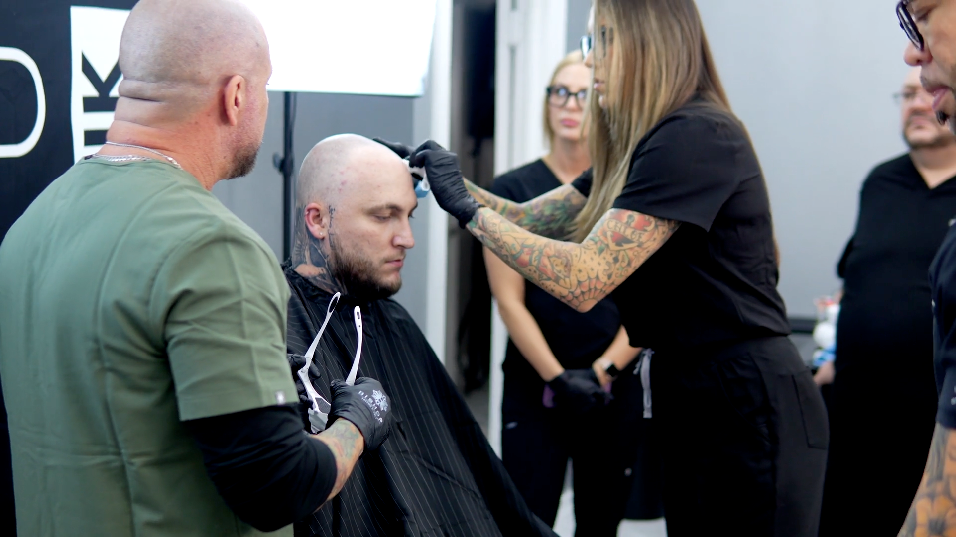 An SMP INK CDA Student Practitioner drawing the reference line on the scalp of  an SMP client in a class setting.