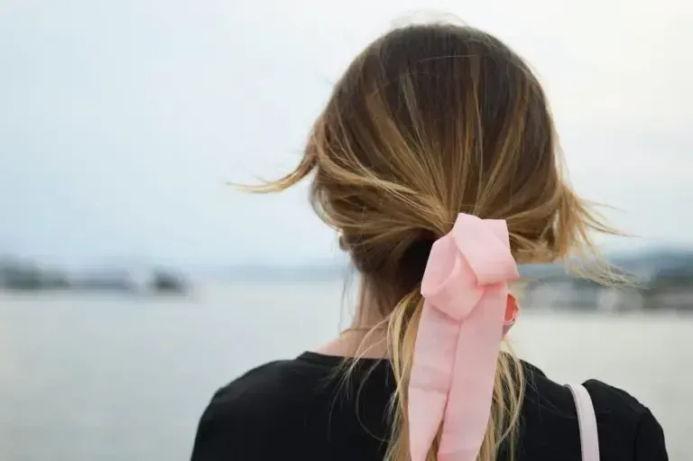 The woman is wearing a pink ribbon in her hair.
