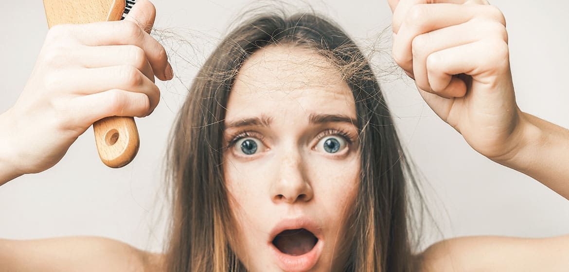 Women holding hair she lost while combing.