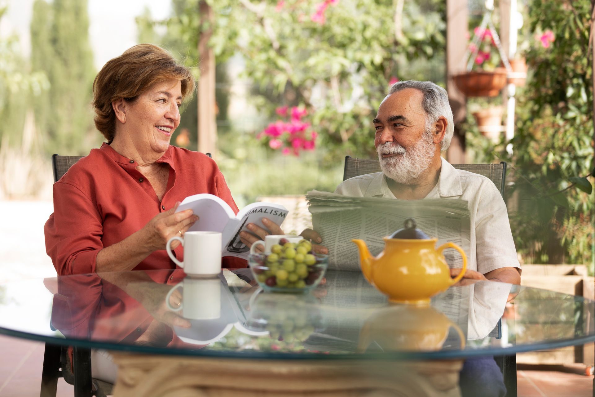 an senior couple is sitting at a table drinking tea, reading and enjoying life