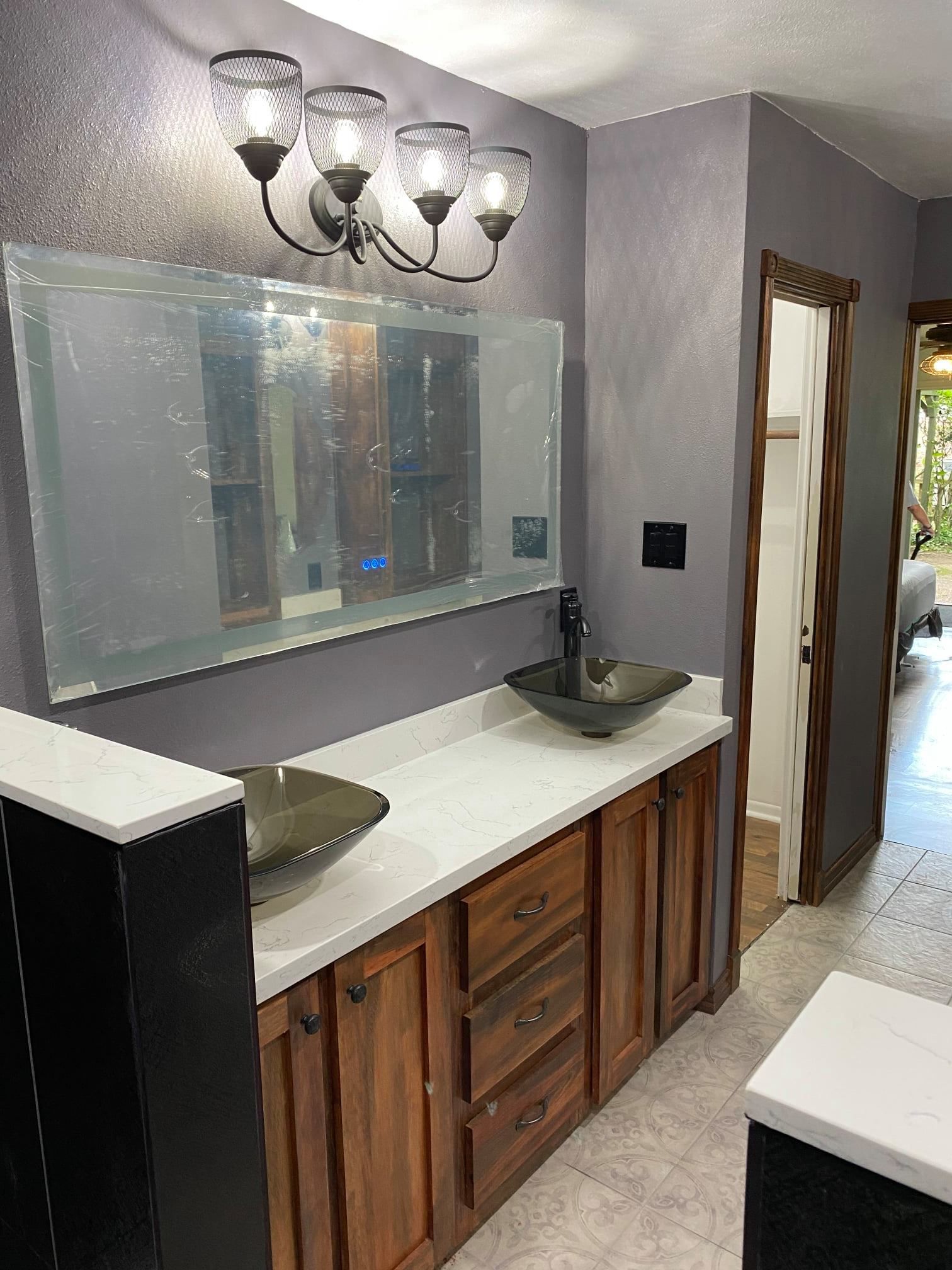 Bathroom vanity with double sinks, large mirror, and wall lights in a gray and wood interior