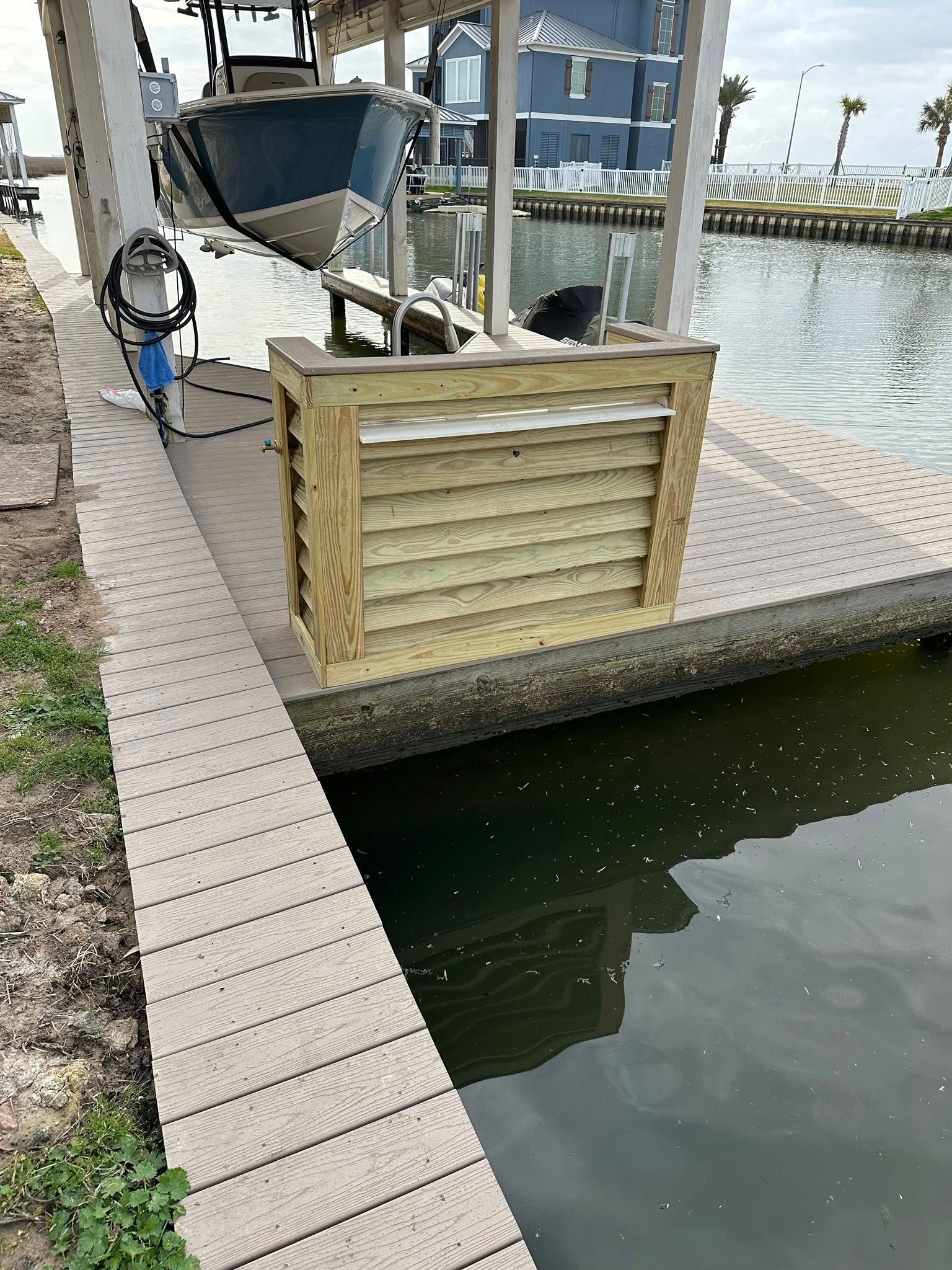 Dockside boat slip with a covered boat lift beside calm water and a wooden barrier.