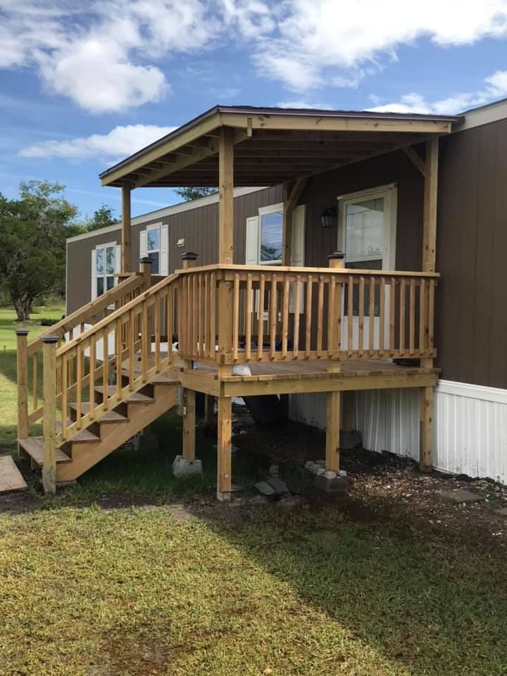 Wooden wheelchair-accessible porch ramp and steps on a beige mobile home under a blue sky