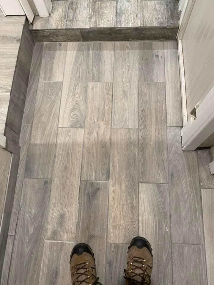 First-person view of feet on gray wood-look flooring at the top of a stair step indoors