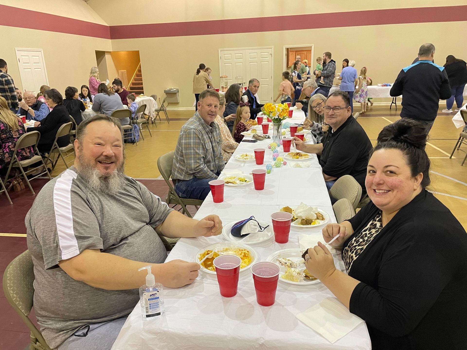 A group of people are sitting at a long table eating food.